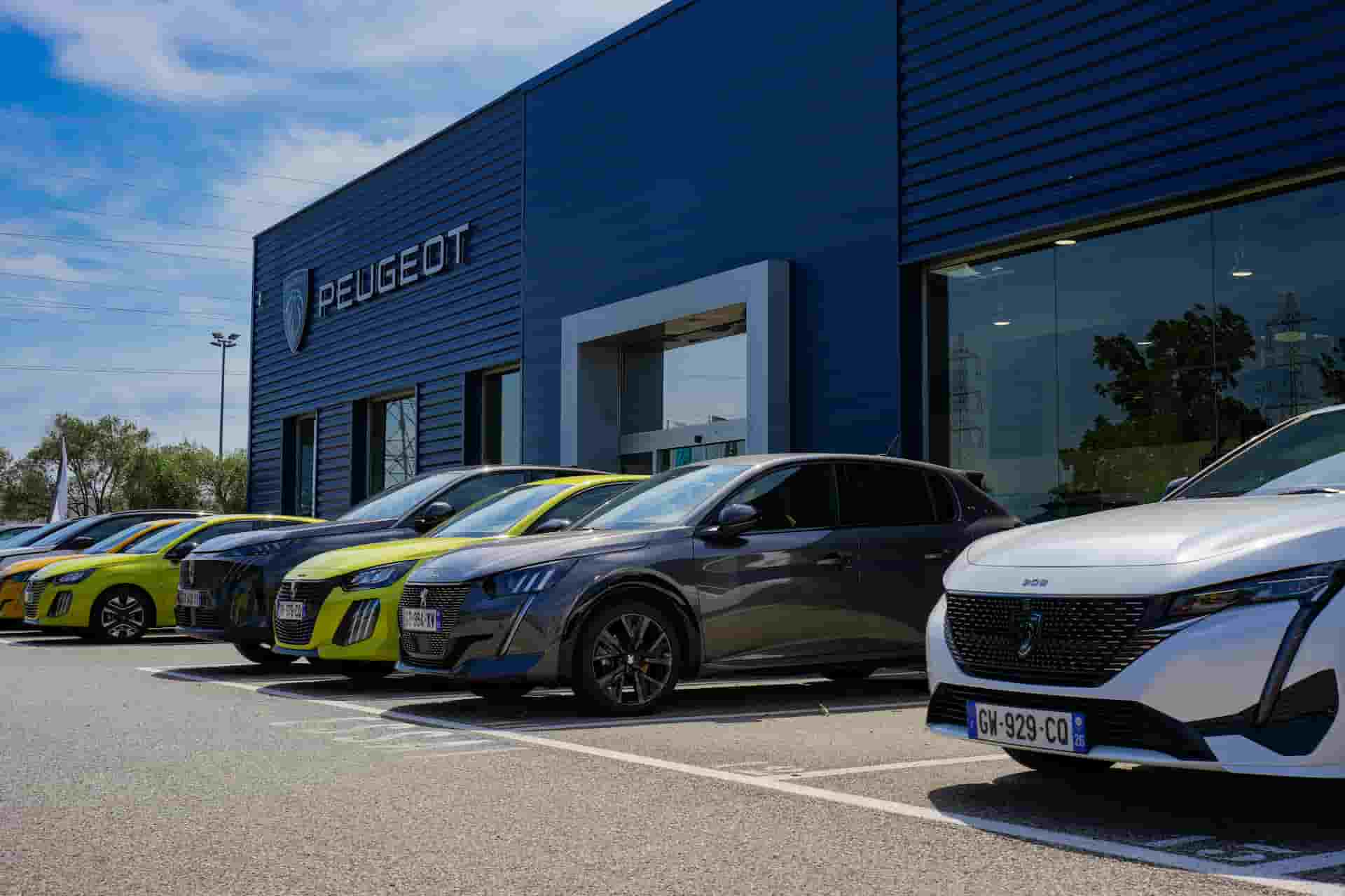 Façade de la concession Peugeot à Valence (26000) avec gamme de véhicules neufs exposés : citadines, SUV et modèles électriques.